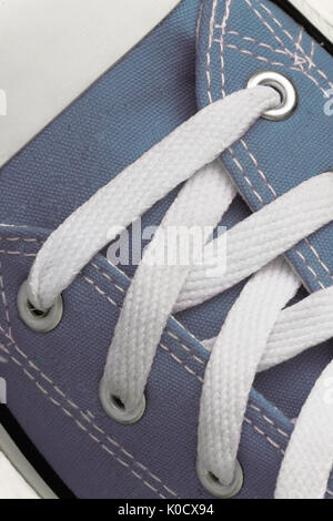 Lacing on a retro sneaker, close-up, on a blue wooden background. Stock Photo