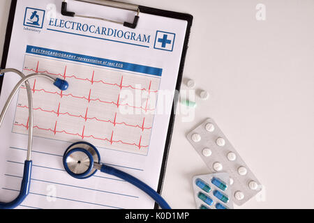 Results of examination of the heart with clipboard presenting electrocardiogram. Ostetoscope and treatment pills on white table. Top view. Horizontal  Stock Photo
