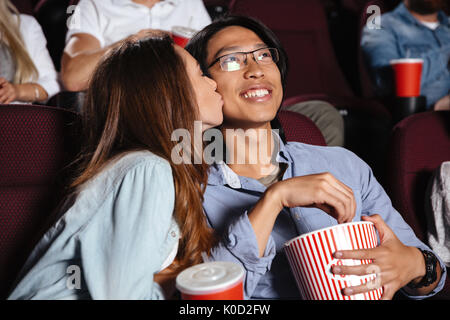 Image of young loving couple sitting in cinema watch film and kissing Stock Photo