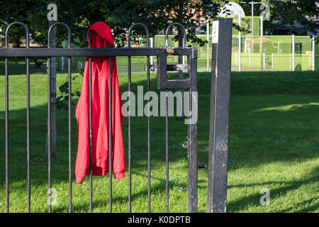 Lost and found. Child's clothing left at a children's playground and hung on the park fence, Nottinghamshire, England, UK Stock Photo