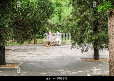 A retired Chinese couple reading newspapers at a quiet corner of the park Stock Photo