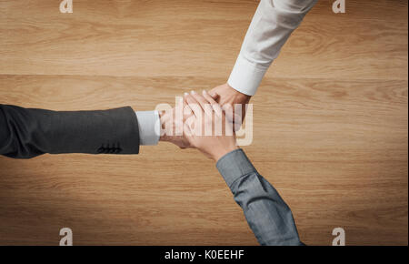 Business people stacking hands close up, wooden desktop on background, unrecognizable people Stock Photo