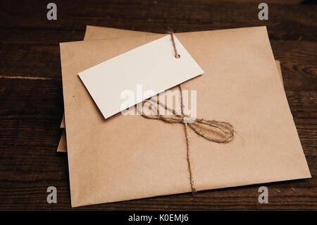 Note from a paper on a cord of an envelope from kraft paper on a wooden table Stock Photo