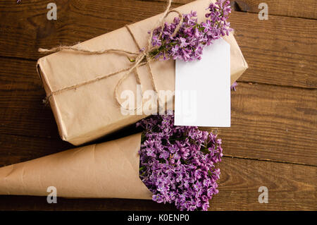 Bouquet of lilacs on a wooden table with a gift box of kraft paper Stock Photo