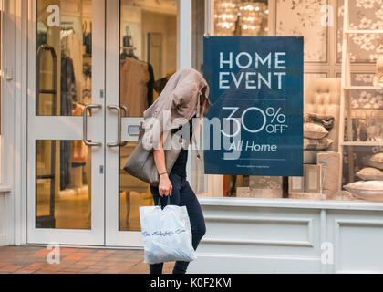 30% off Home Event in Preston, Lancashire. 23rd Aug, 2017. UK Weather. A Miss Selfridge shopper covers her hair with a coat in heavy rain.  Rainy start to the day in the city centre with a local forecast of early morning heavy showers followed by brighter conditions later. Credit; MediaWorldImages/AlamyLiveNews. Stock Photo