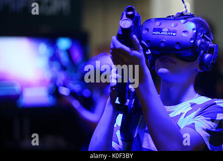 Cologne, Germany. 23rd Aug, 2017. Visitors to the Gamescom playing the computer game Hologate with a VR (Virtual Realitiy) headset in Cologne, Germany, 23 August 2017. The computer games fair Gamescom takes place between 22 and 26 August 2017. Photo: Oliver Berg/dpa/Alamy Live News Stock Photo