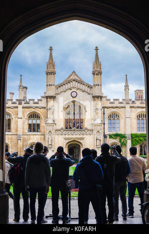 Cambridge tourists, a group of tourists stand under the arched entrance of Corpus Christi College to look at the New Court building, UK. Stock Photo