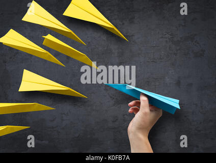 Concept - Being different. A man about to throw a paper plane in a different direction to everyone else. Stock Photo