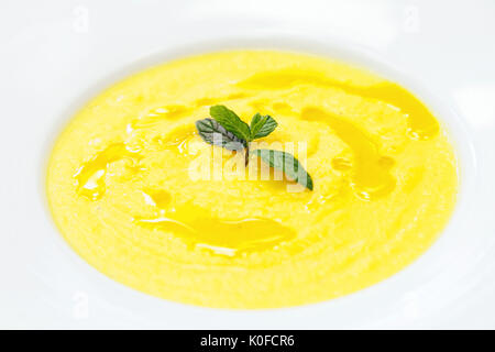 Pumpkin potage served in a white plate, decorated with mint leaves Stock Photo
