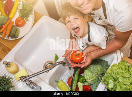 Father with little son washes vegetables on the kitchen before eating Stock Photo