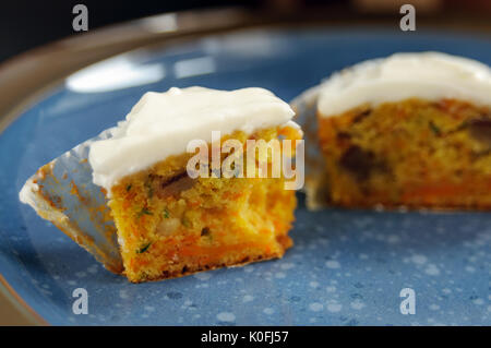 Zucchini and carrot cupcakes with Philadelphia cheese cream on blue plate on black surface Stock Photo