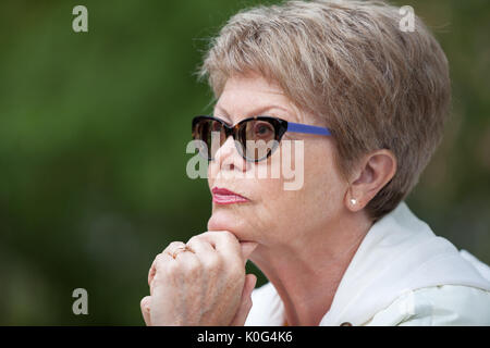 Closes up side view portrait of an elderly woman in glasses thinking with hands under head Stock Photo