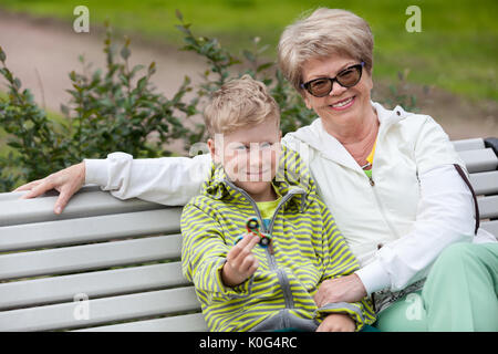 Grandmother presenting boy the new spinner for playing, happy grandson showing the gadget Stock Photo