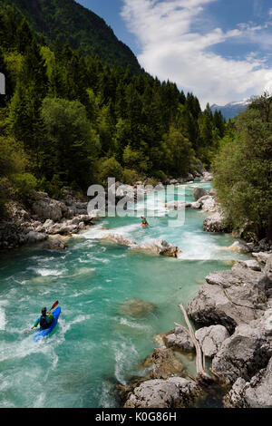 Kayakers shooting the cold emerald green alpine water of the Upper Soca River near Bovec Slovenia with Kanin mountains in the Julian Alps Stock Photo
