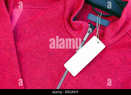 White blank clothing label tag on a new red jacket with zipper Stock Photo