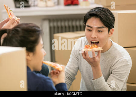Portrait of young smiling businessman and his coworkers eating pizza at office Stock Photo
