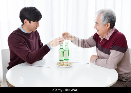 Side view portrait of smiling son and his senior father drinking Stock Photo