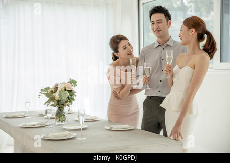 Three young smiling friends with champagne enjoying a party Stock Photo