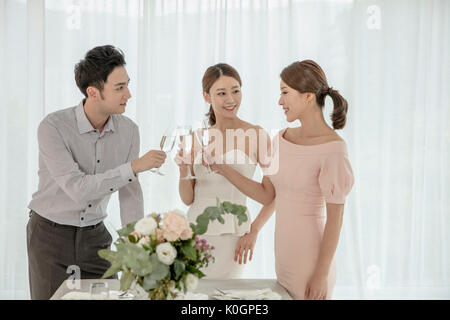 Three young smiling friends toasting with champagne glasses at party Stock Photo