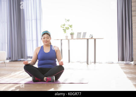 Young fat woman doing yoga Stock Photo
