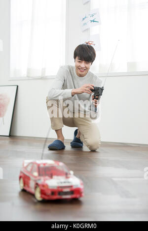 Smiling male kidult playing with toy car Stock Photo