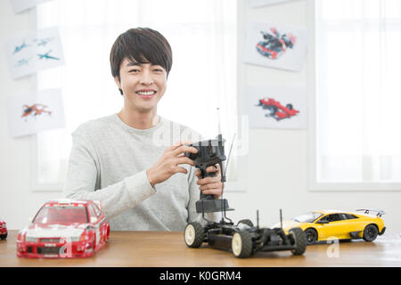 Portrait of smiling male kidult playing with toy cars Stock Photo