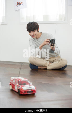 Smiling male kidult playing with toy car Stock Photo