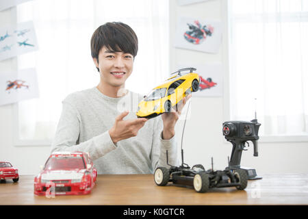 Portrait of smiling male kidult playing with toy cars Stock Photo