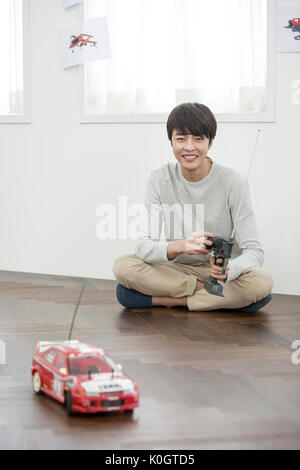 Smiling male kidult playing with toy cars Stock Photo