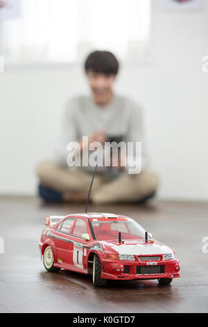 Smiling male kidult sitting playing with toy cars Stock Photo