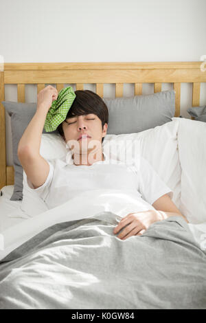 Single man sick putting an ice pack on his head Stock Photo