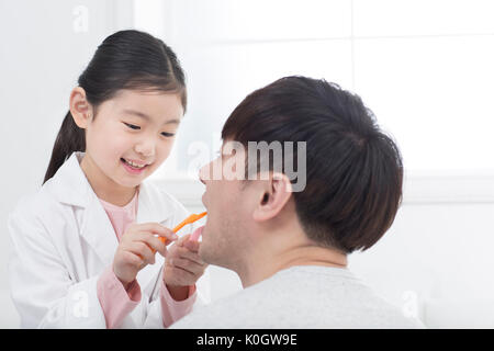Portrait of smiling girl and her father playing hospital Stock Photo