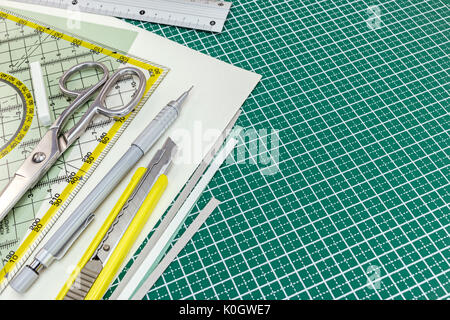 Sharp cutting blade on a green grid hobby mat, measured in inch