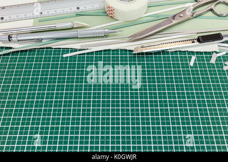 ruler, cutter, scissors, tape, pencil, paper sheet on green cutting mat background Stock Photo