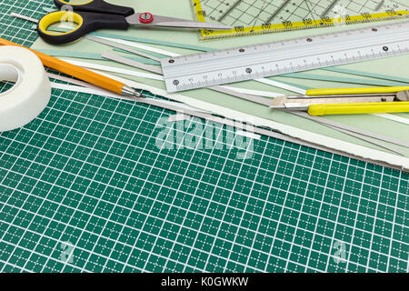 school and office stationery on cutting mat: cutter, pencil, ruler, scissors, tape, paper sheets Stock Photo