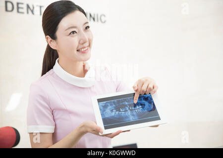 Portrait of smiling dental hygienist showing an x-ray picture on tablet Stock Photo