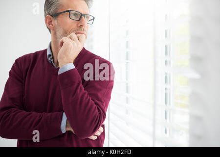 Thoughtful man looking through the window Stock Photo