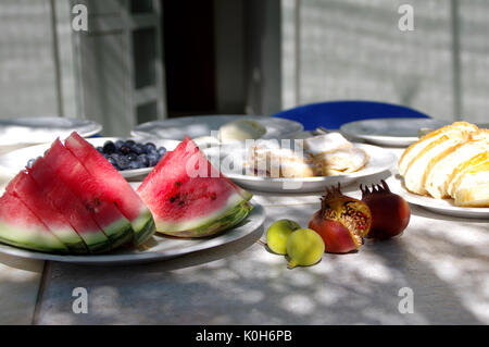 Vegetarian food - a piece of watermelon, figs and other fruits on the plates Stock Photo