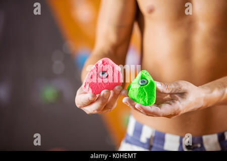 Rock climber demonstrating new bolt-on climbing holds. Image with selective focus. Stock Photo