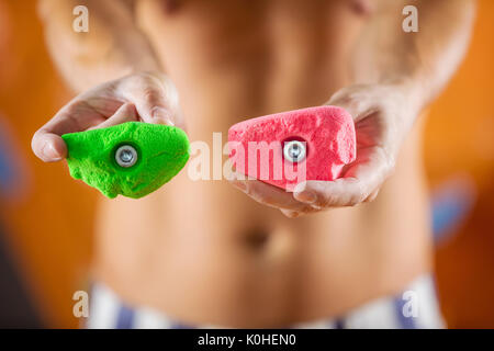 Rock climber demonstrating new bolt-on climbing holds. Image with selective focus. Stock Photo