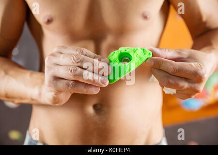Rock climber demonstrating new bolt-on climbing hold in indoor climbing gym Stock Photo