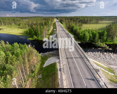 Asphalt country road across small river. Bridge over water and swamp. Karelia, Russia Stock Photo