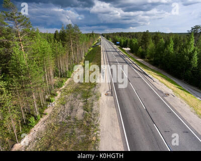Empty asphalt country road in northern Karelia. Thunderclouds over forest. Russia Stock Photo
