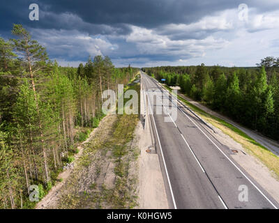 Country asphalt road among forests. Rain clouds in the sky. Summer season, Karelia, Russia Stock Photo