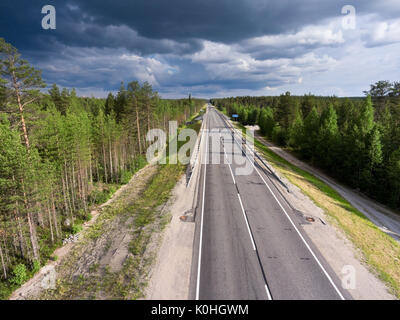 View from above at country asphalt highway among northern woods. Rain clouds in the sky. Summer season, Karelia, Russia Stock Photo