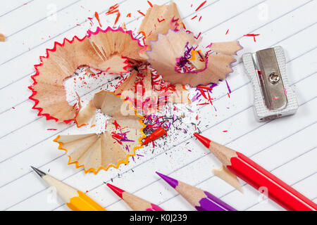 Colouring pencil shavings on a lined note pad with pencils and a pencil sharpener Stock Photo