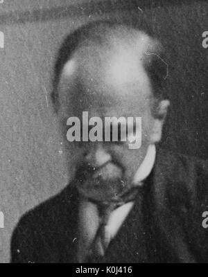 Head shot of original faculty member of Johns Hopkins University Medicine, William Osler, wearing a dark suit and a dark tie with a white shirt, looking downwards with a serious facial expression. 1902. Stock Photo