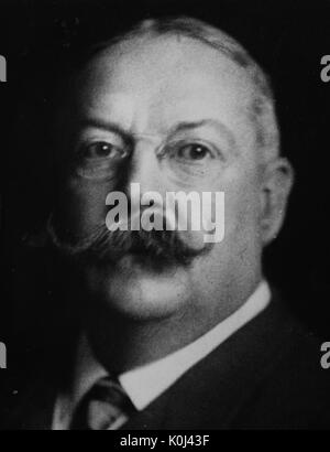 Head shot of original faculty member of Johns Hopkins University Medicine, John Noland Mackenzie, wearing a dark suit and a patterned tie with a white shirt, wearing frameless circular glasses, sporting a thick handlebar mustache, with a serious facial expression. 1915. Stock Photo