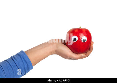 Female hand holding red apple with googly eyes isolated on white background with copy space. Healthy food and lifestyle concept Stock Photo