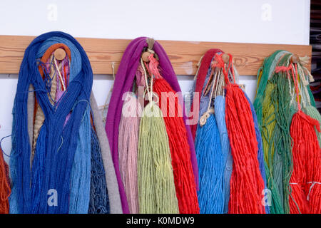 Hand dyed and handspun wool with a range of vibrant colours hanging on pegs in studio Stock Photo